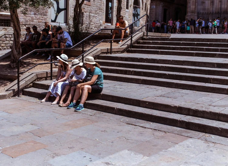 three people are sitting on stairs in front of a building