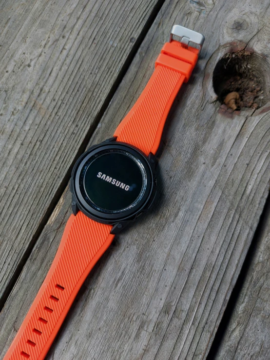 an orange watch sits on top of a wooden table