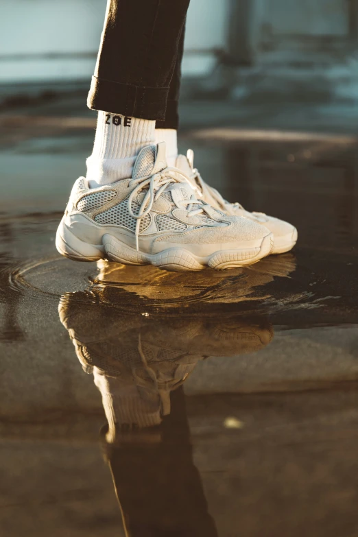 the legs and ankles of a man in sneakers reflected in dle