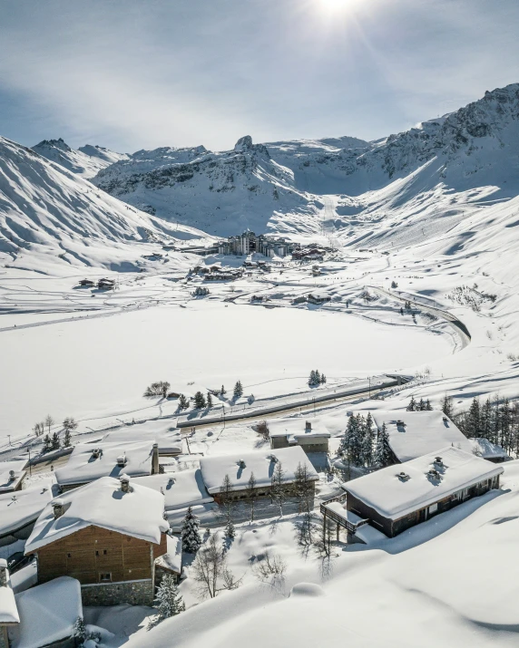 the snow covered mountains are behind houses and small village