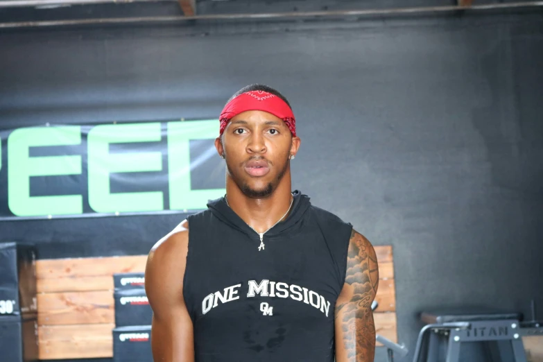 a black man with a red head band is standing by some speakers