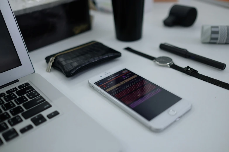 a tabletop with a cell phone, watch, and pen