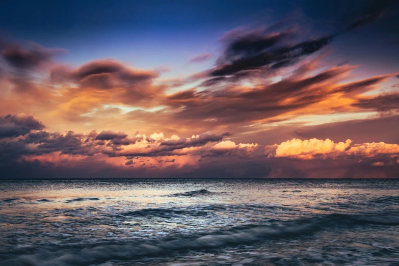 some very beautiful clouds above a body of water