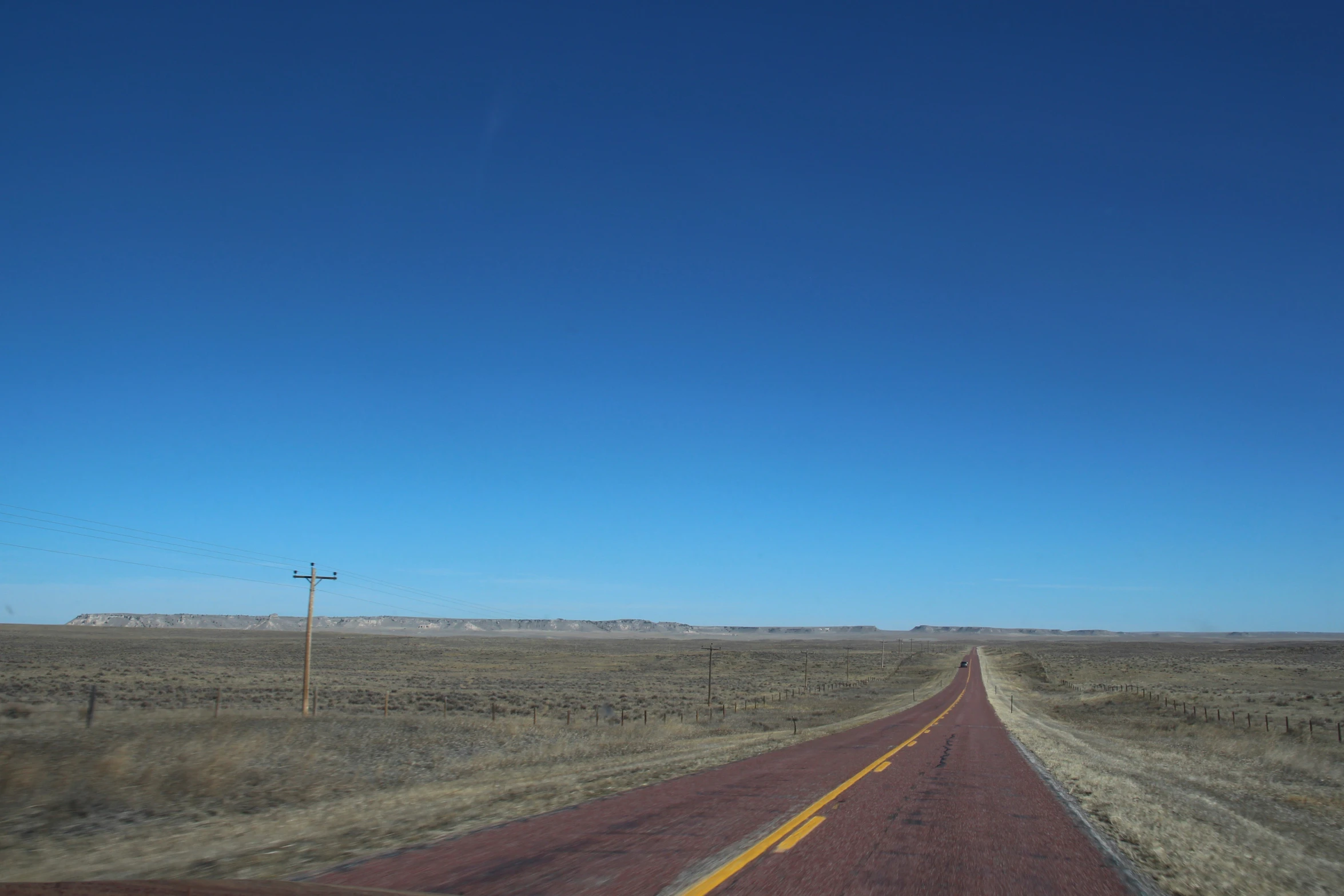 a lone bus traveling on an empty country road