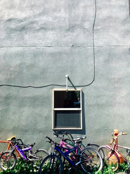 colorful bikes lined up against a grey wall