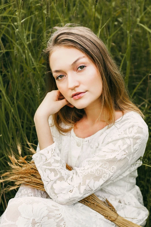 a woman sitting down in the grass with her hand on her shoulder