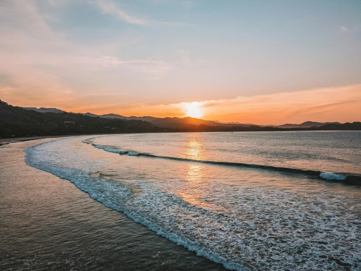 the sun setting over the ocean as seen from a beach