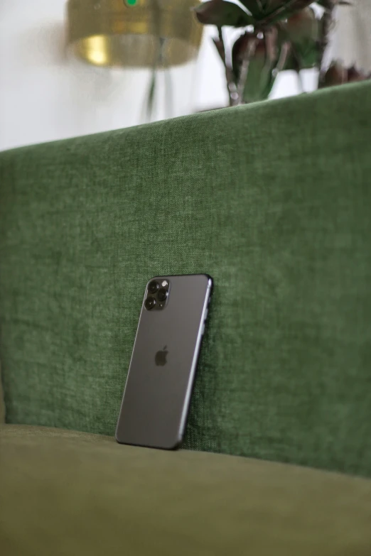 an iphone phone leaning against a couch in the corner