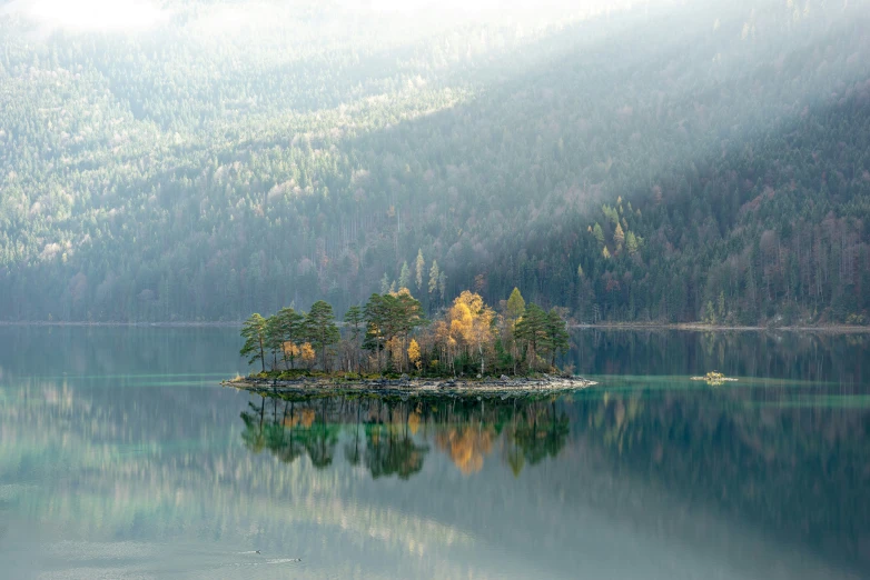 an island in the middle of a lake surrounded by mountains