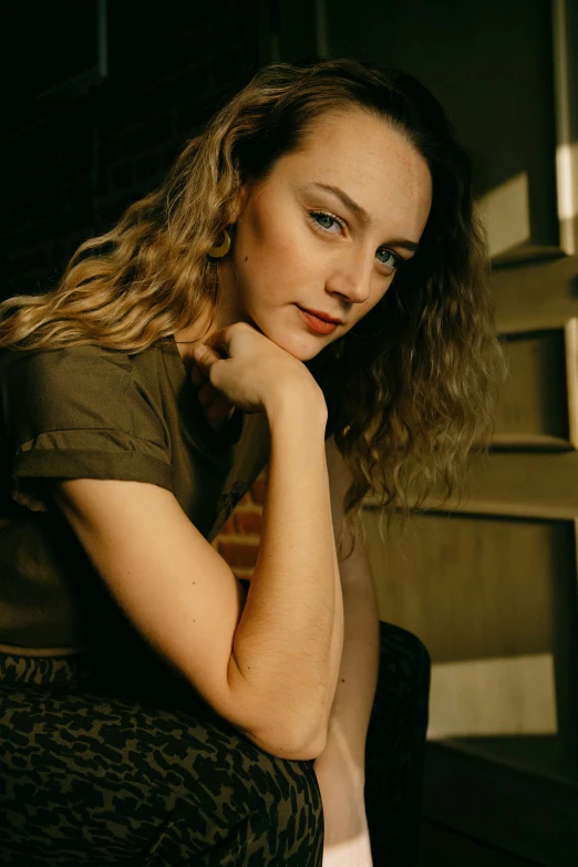 there is a young woman with long curly hair sitting on a chair