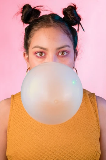 woman blowing bubbles off her face on pink background