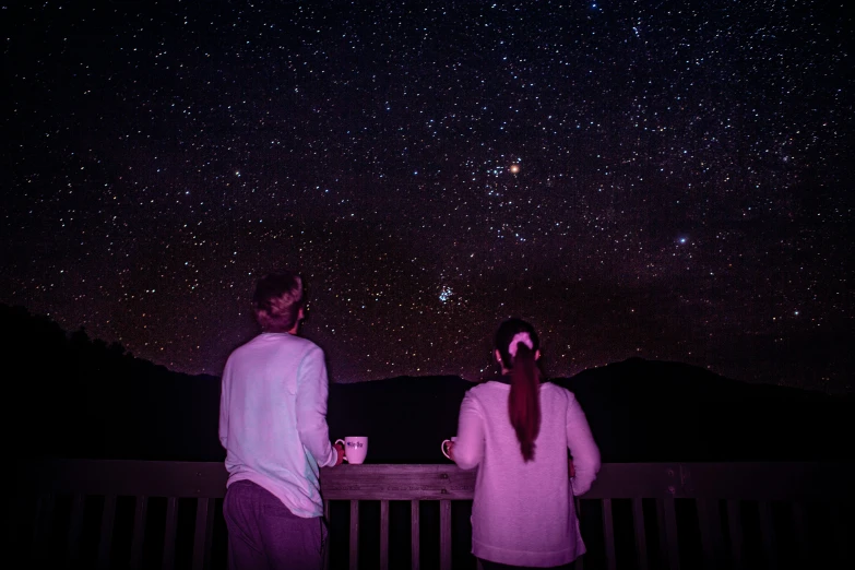 two people look into the night sky at the stars