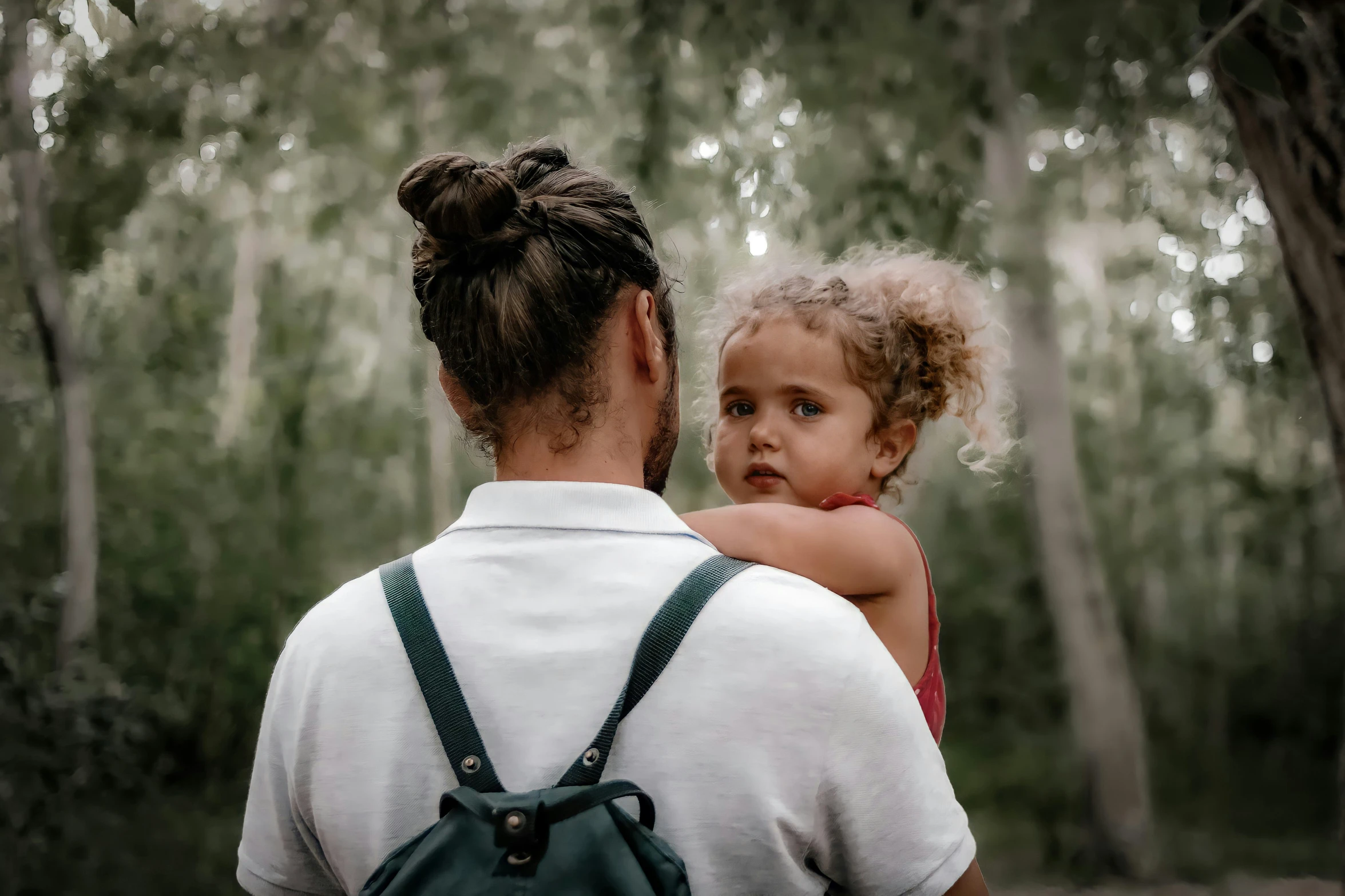 the man is holding his daughter in a forest