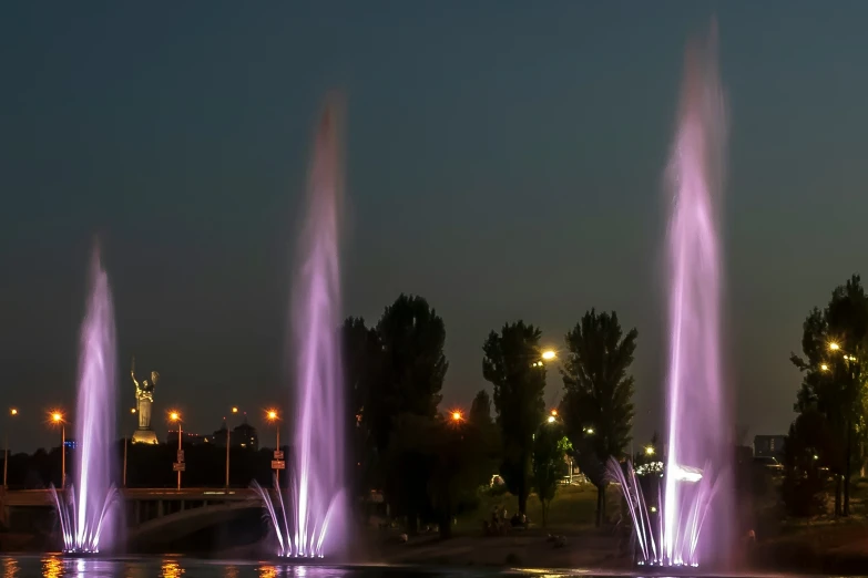 a series of water fountains at night near the shore