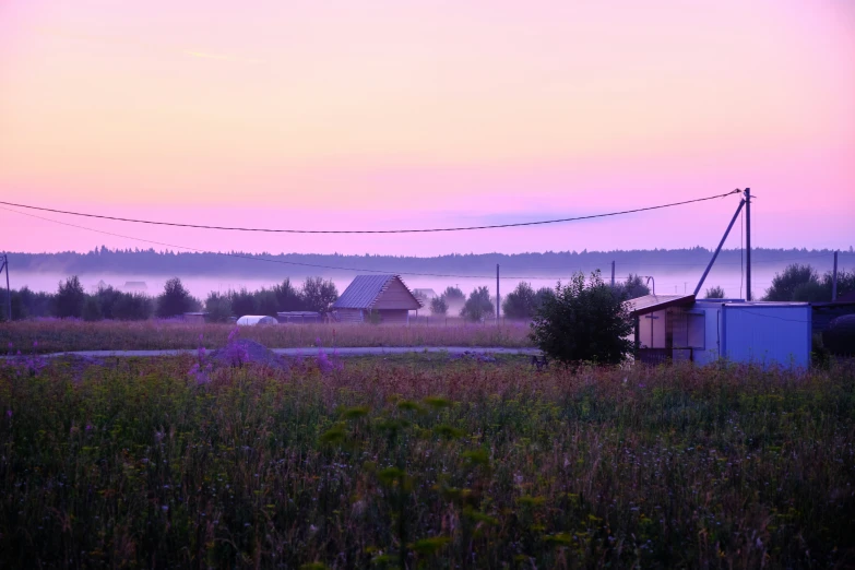 a farm in a field with cars and houses in the background