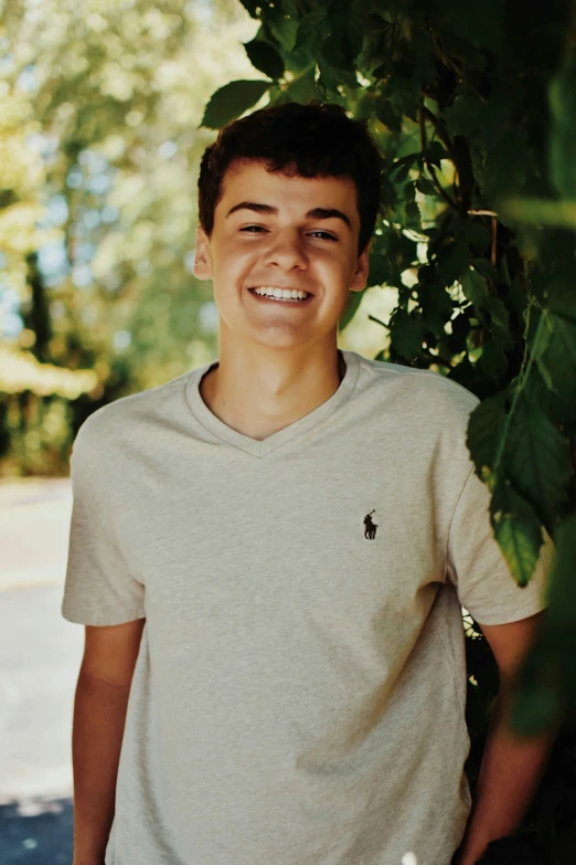 a boy standing under a tree in a park