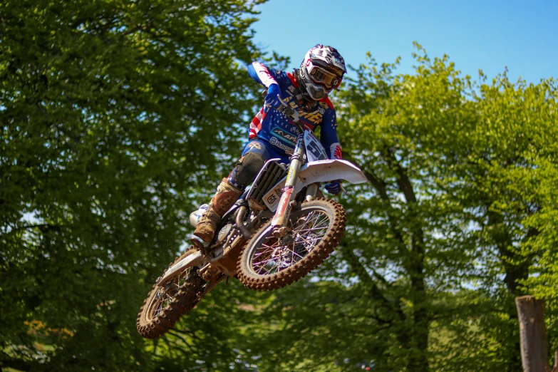 a man riding on the back of a dirt bike through trees