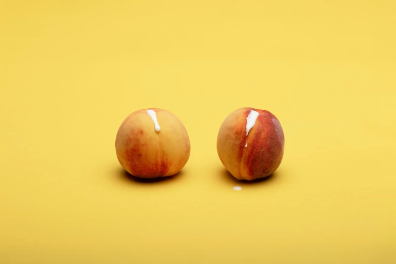 two ripe apples on a yellow surface together