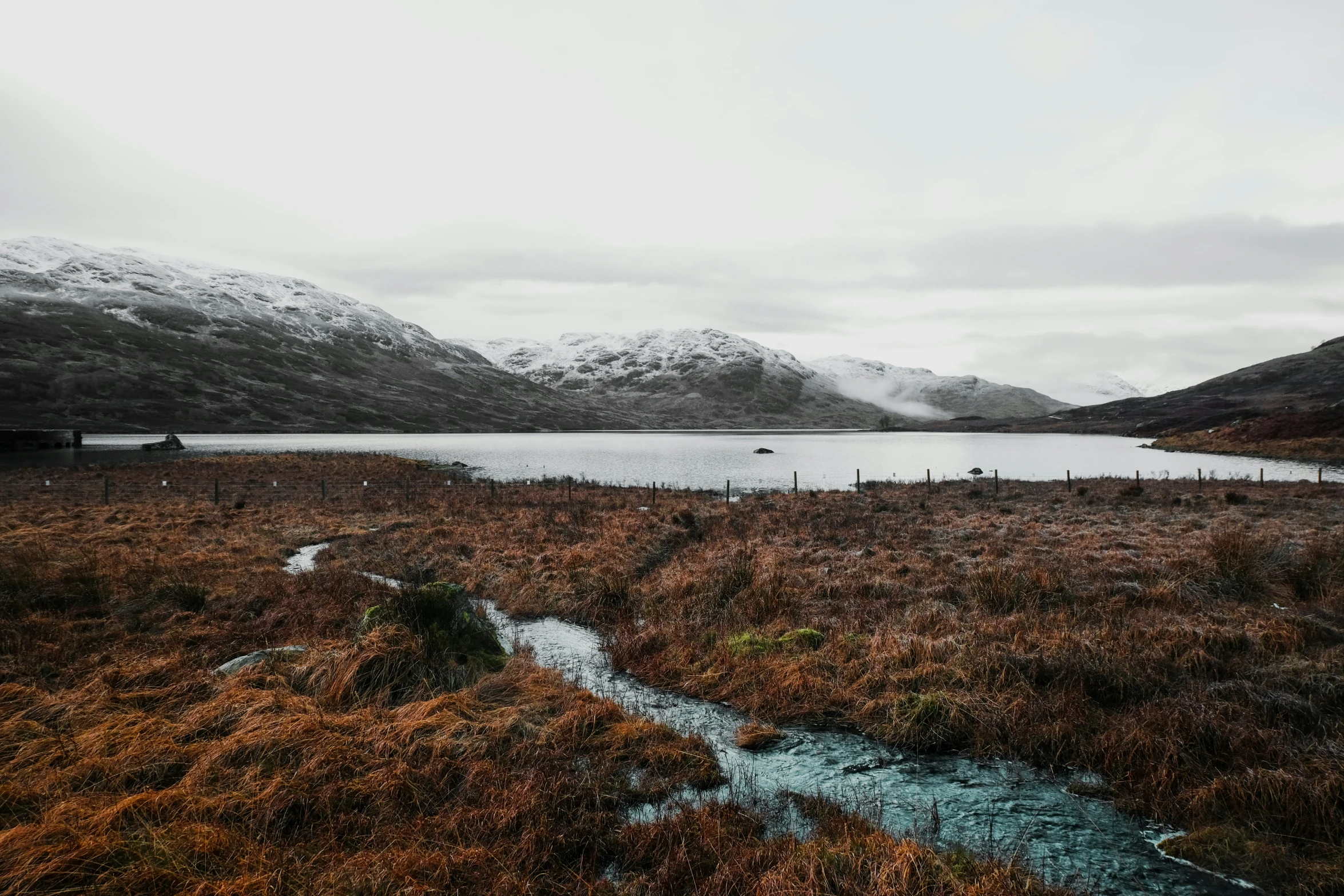 a small stream running through an open land near a mountain