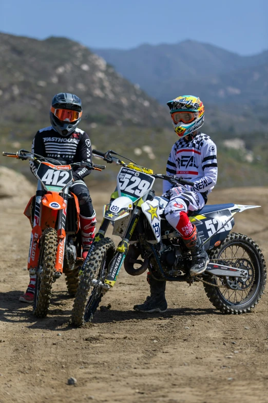 two motorcyclists are in the dirt on their bikes