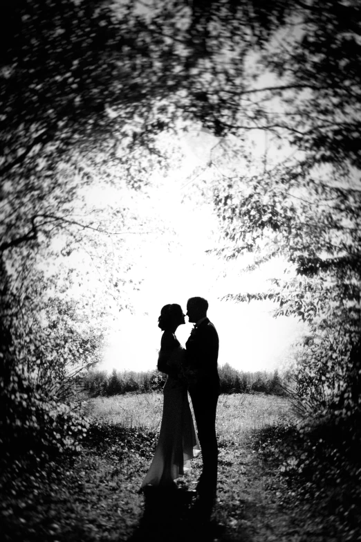 couple in front of tree's with sun coming through their leaves