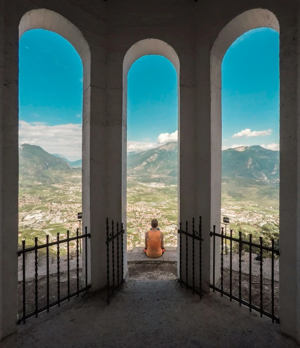 man in red sitting on the steps overlooking valley