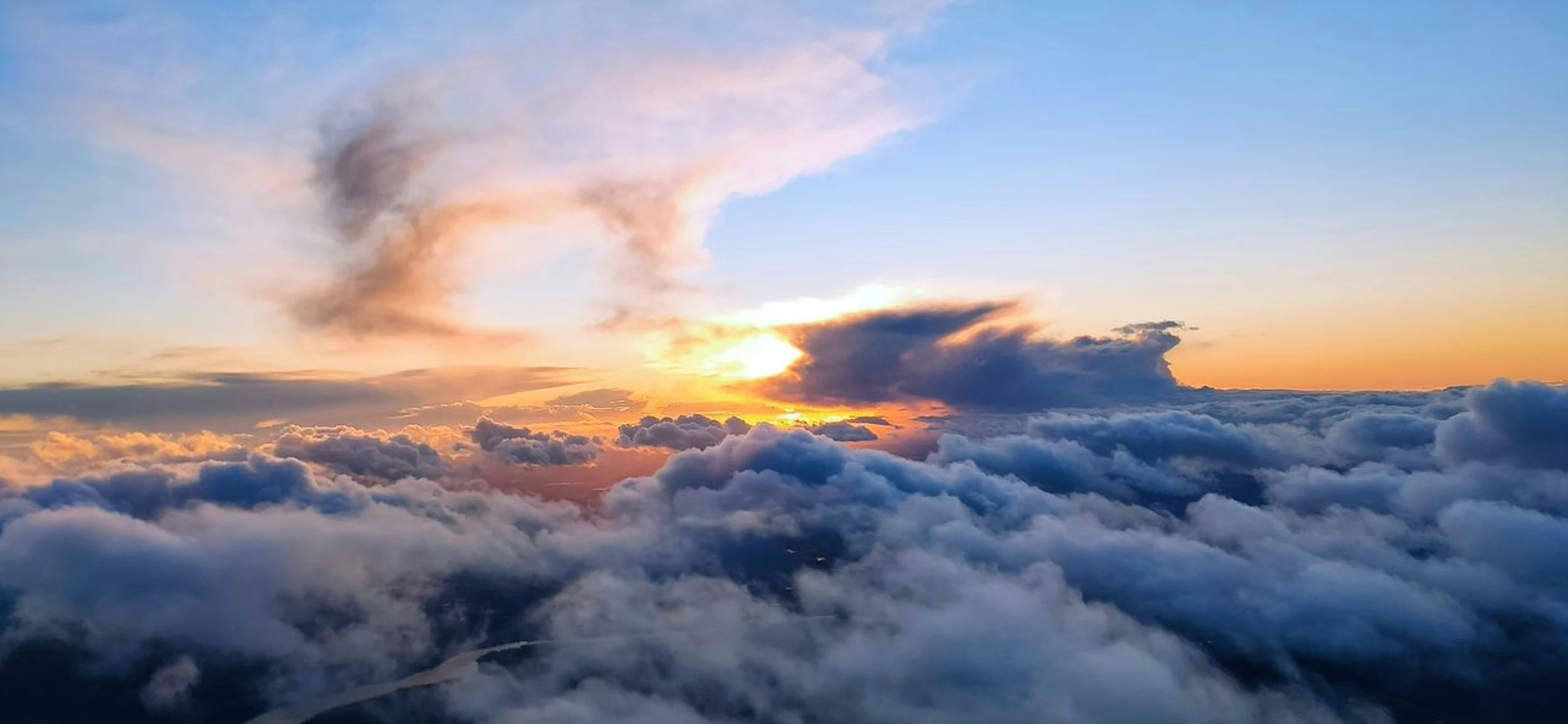 the sun sets in the clouds on top of a city