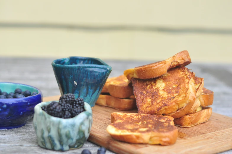 small bowl with berries and toast sitting on a  board