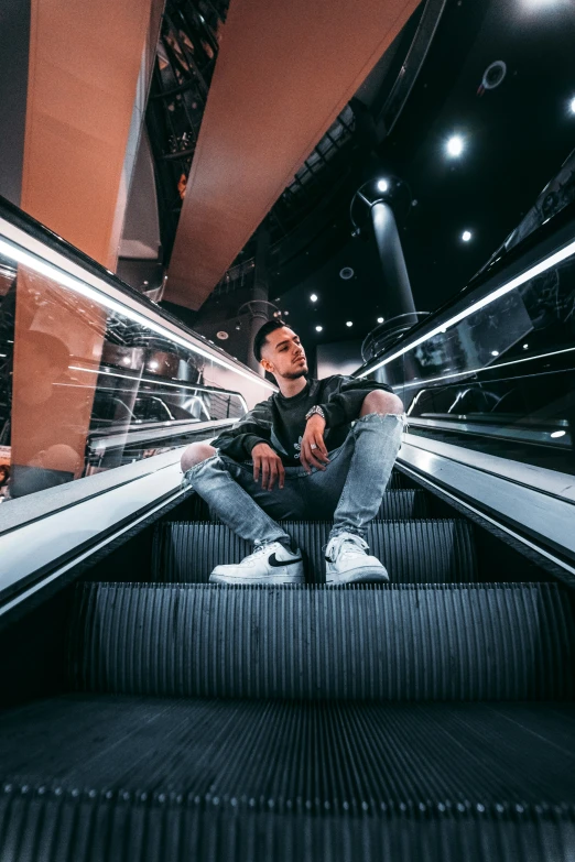 a man sitting in an escalator inside of a train station