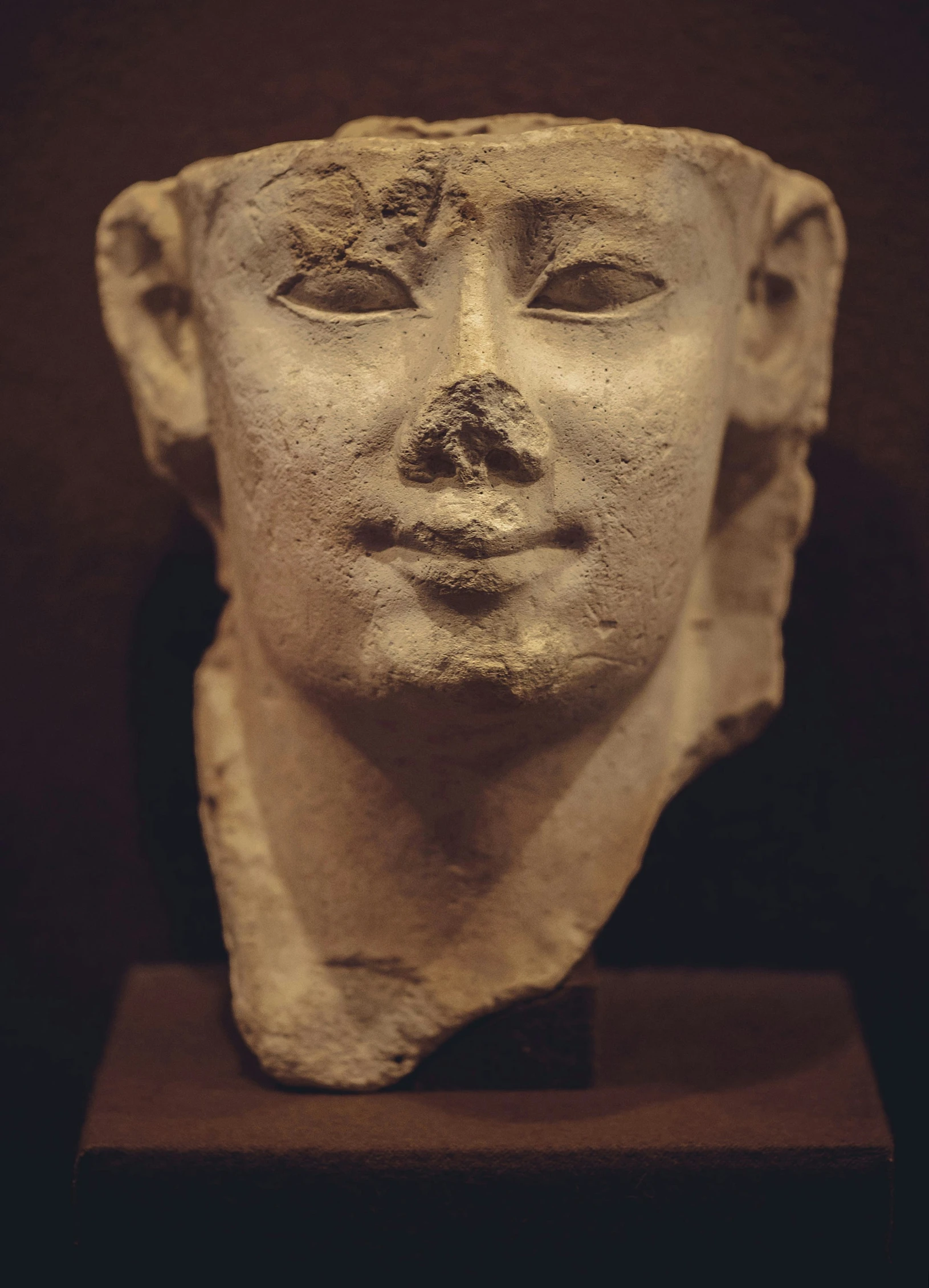 a close up of a face on a white stone