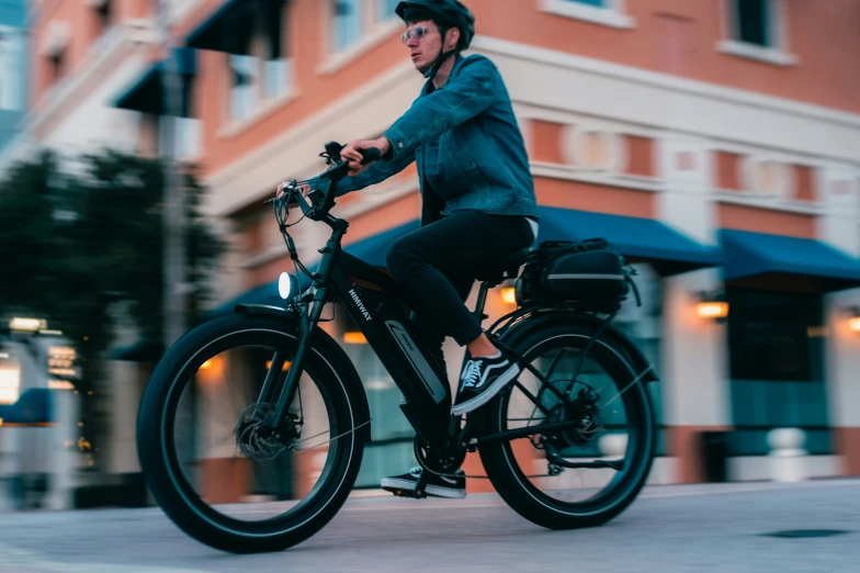 man riding a bike on the road by a tall building