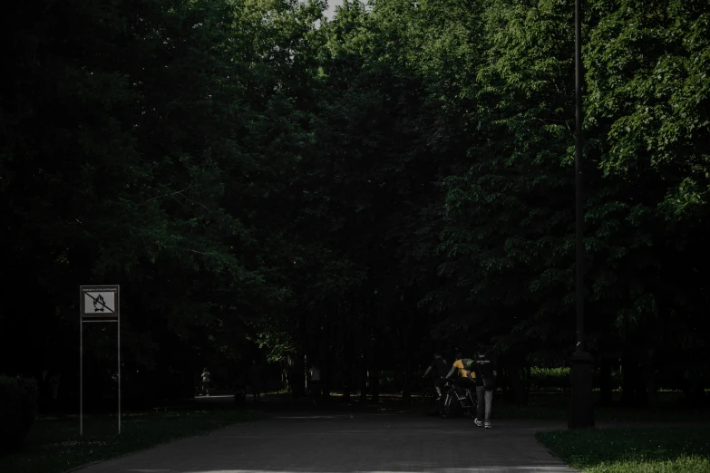 two people standing with a bike on the sidewalk next to some trees