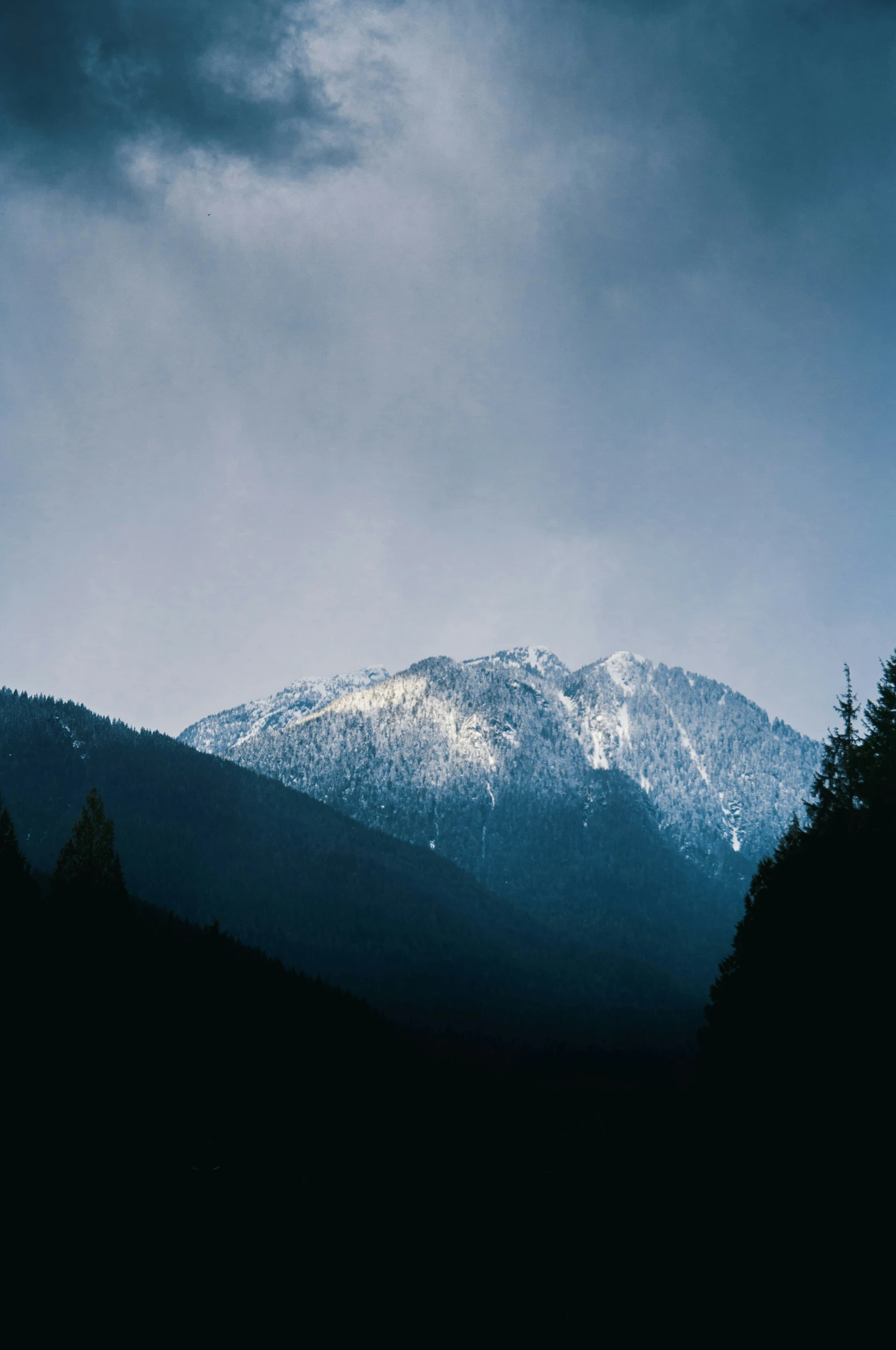 a snow covered mountain is seen with clouds in the sky