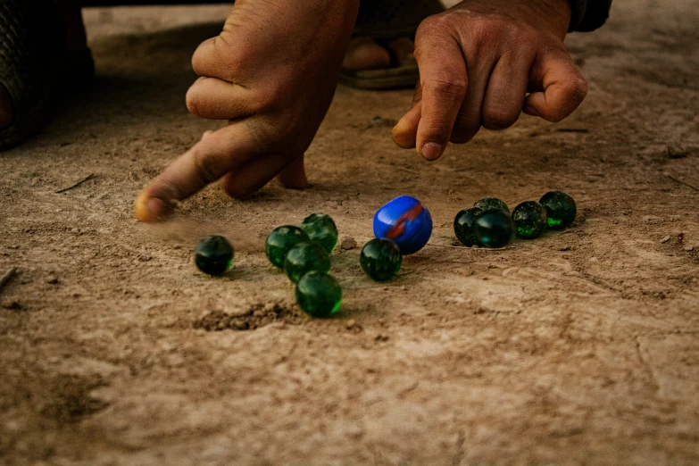 a person pointing down at small blue and green beads