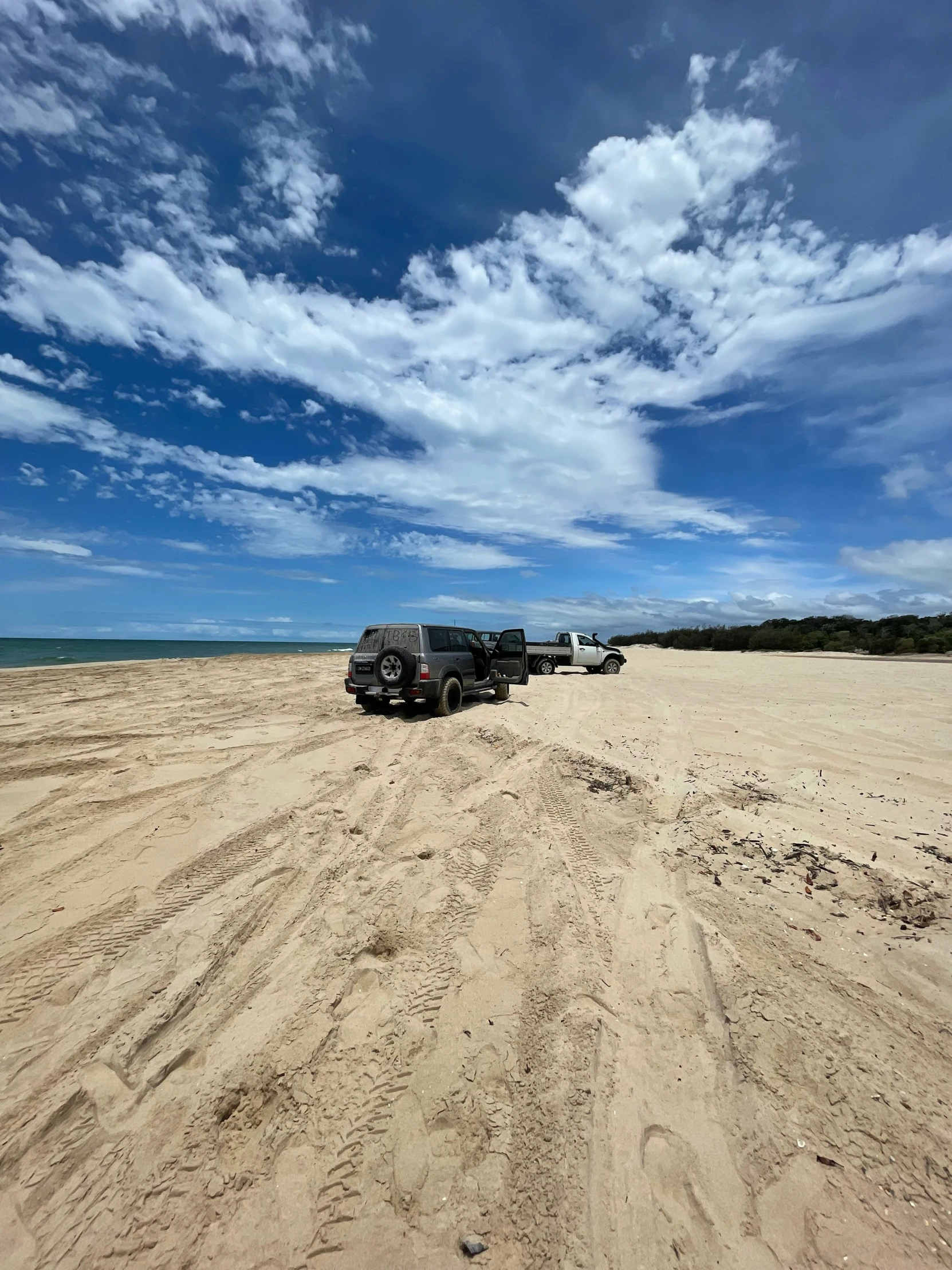 three vehicles parked in the dirt under blue skies