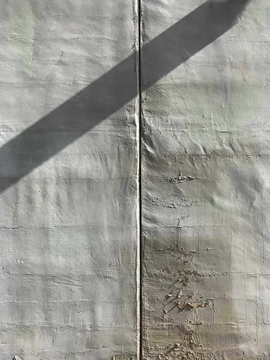 a shadow from an umbrella cast on a concrete wall