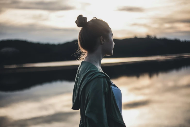 a beautiful woman stands in front of water