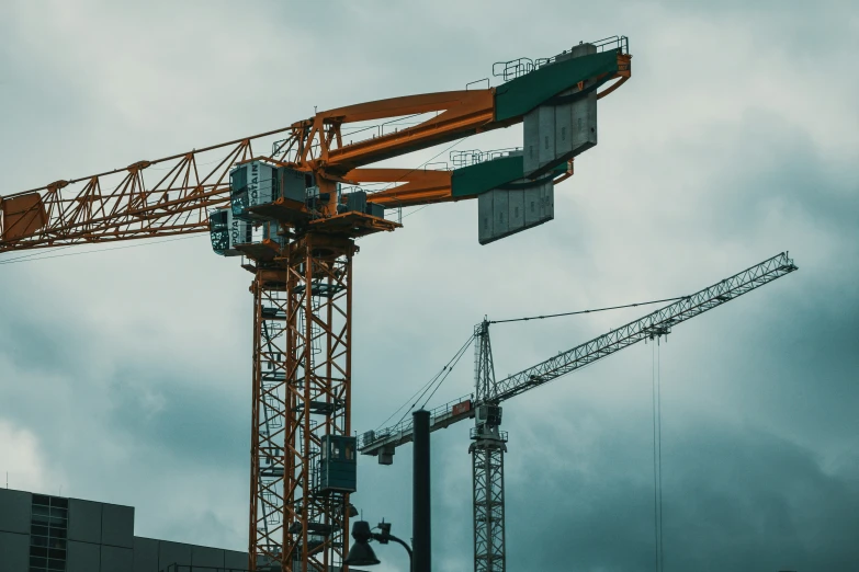 many cranes against a grey sky on the street