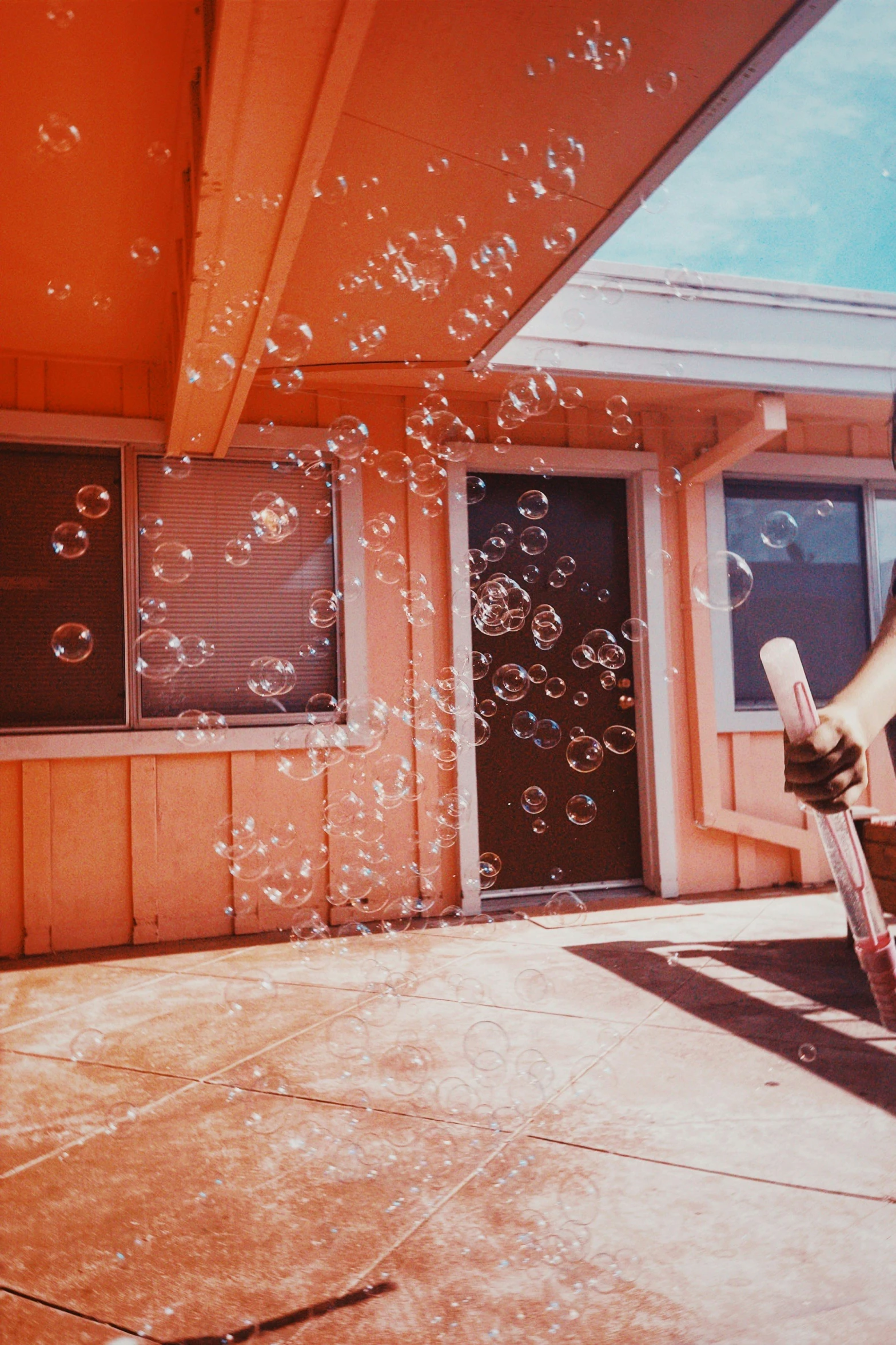 a boy holds a stick outside his house