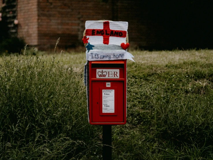 a red and white post box in the middle of grass