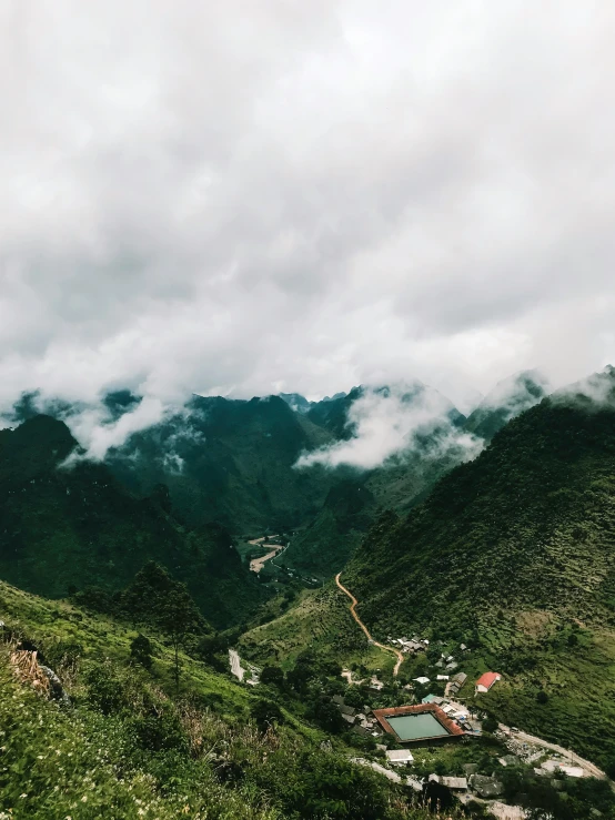 mountains with a body of water in it and clouds rolling over