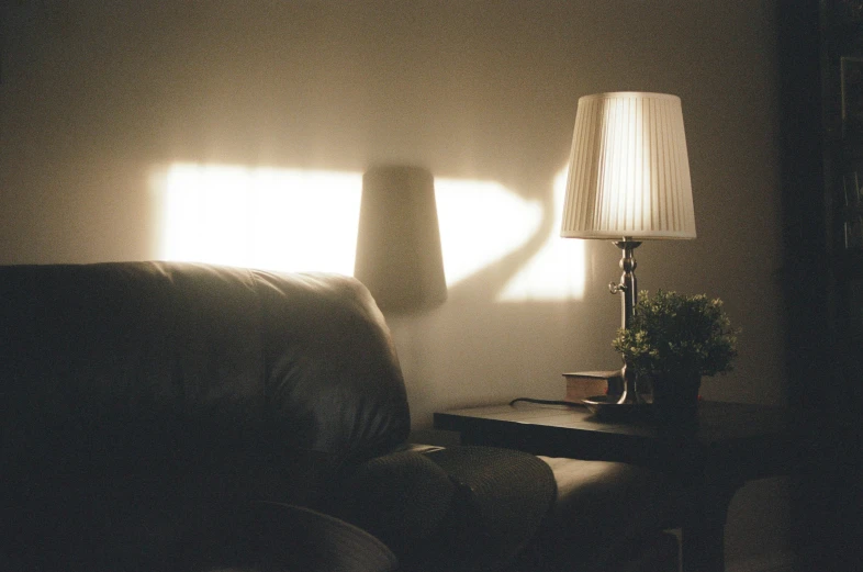 a dark room has a table and lamp near it