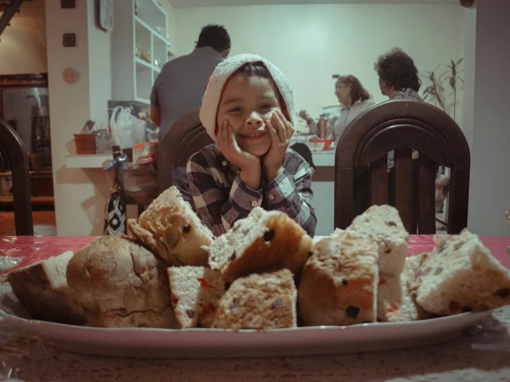 the young child smiles with half eaten bread on the table