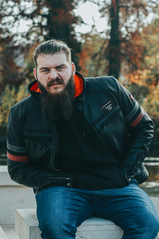 a man with a beard sitting on a concrete block