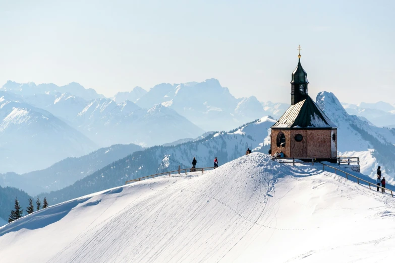 two skiers stand at the top of a snowy mountain