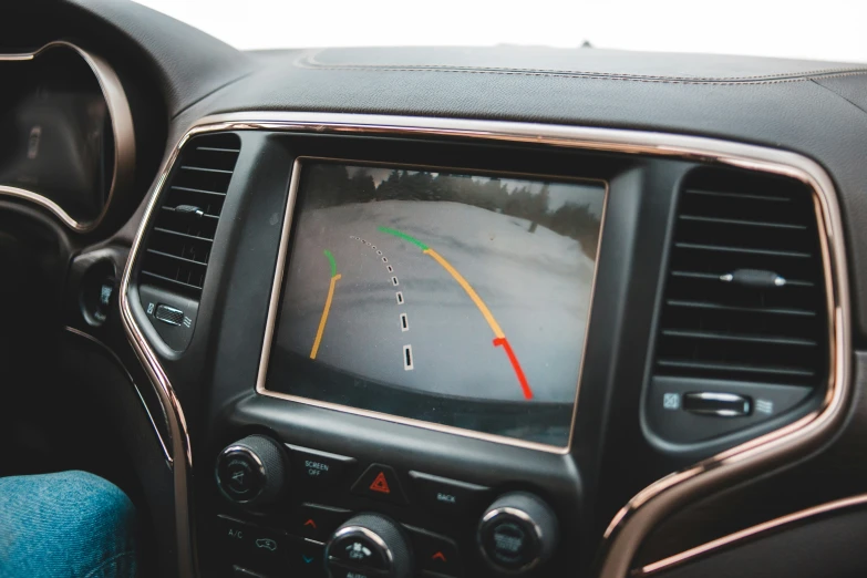 the dash screen inside of a car is marked with a yellow arrow and the other hand is pressing the ons