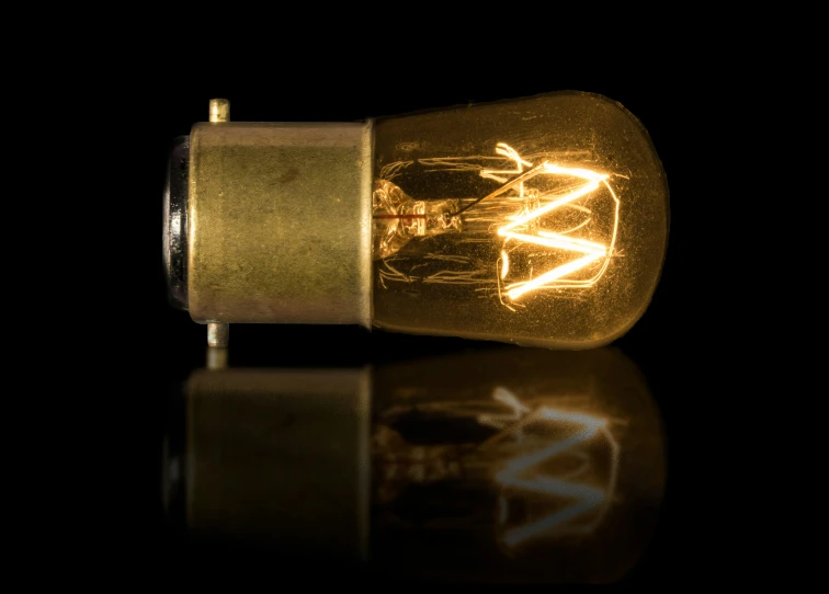 a light bulb with its reflection on a black surface