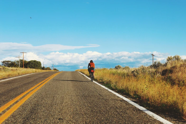 a person on a bike rides down a lonely road