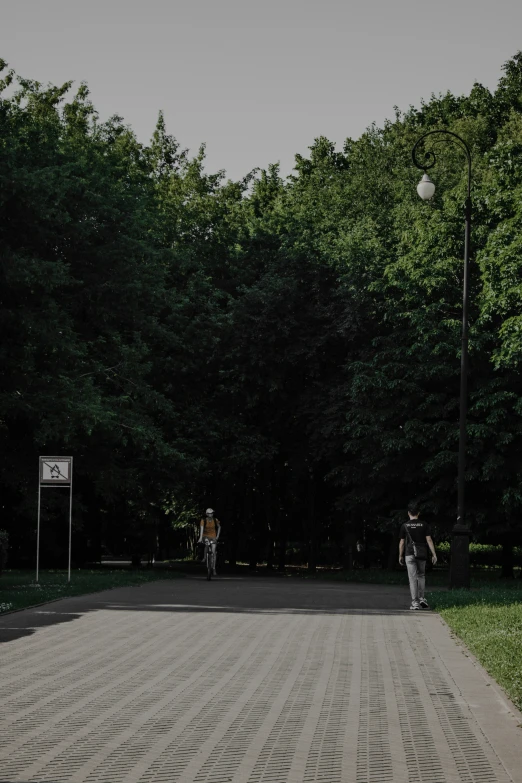people walking down a path in a park near a basketball hoop