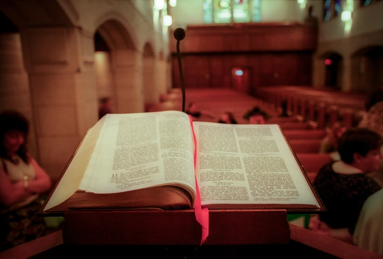 a open bible is sitting on a table with a pink cloth
